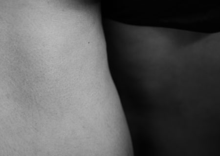 A black-and-white abstract photo of a fat person's thighs. One is in the light, while the other is in deep shadow.