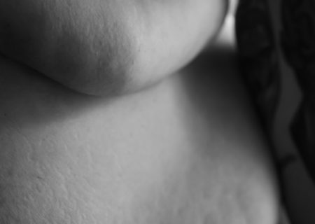 A close-up of a fat woman's side and belly rolls in black and white, with a bit of a bra and arm showing.