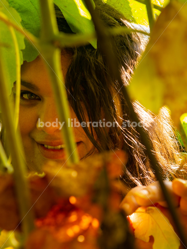 Size-Diverse Stock Photo: Woman Smiling Through Vines - Body liberation boudoir, portraits, stock, HAES & more | Seattle