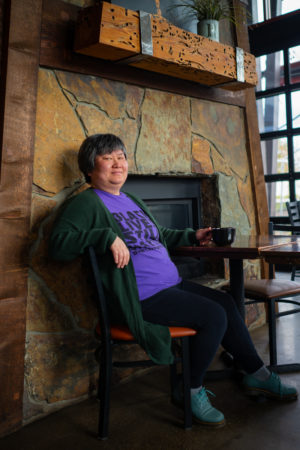 A fat person siting in front of a fireplace indoors in the Pacific Northwest