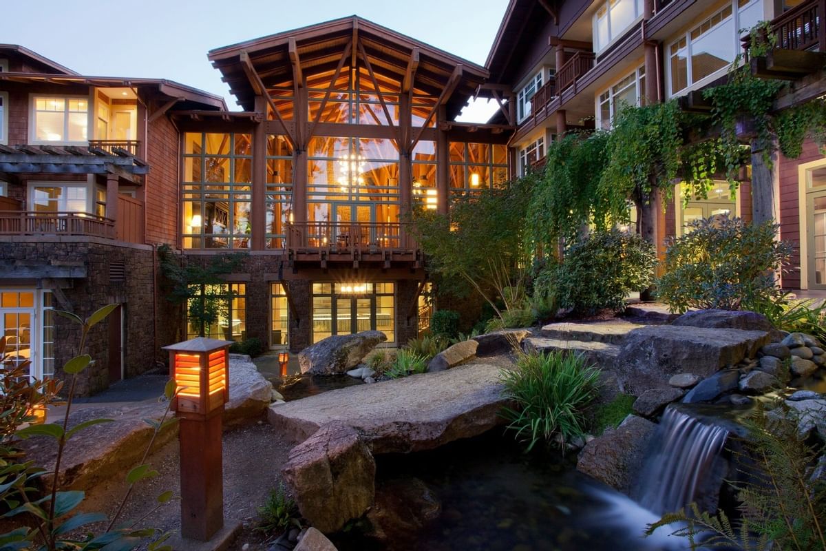 A rustic Pacific Northwest hotel shown at dusk, with lots of wood and glass.