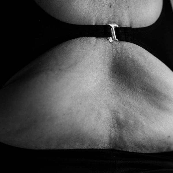 A close-up of a woman's back. She's wearing a swimsuit with a silver buckle, and the image emphasizes the texture and fine wrinkles of her skin.