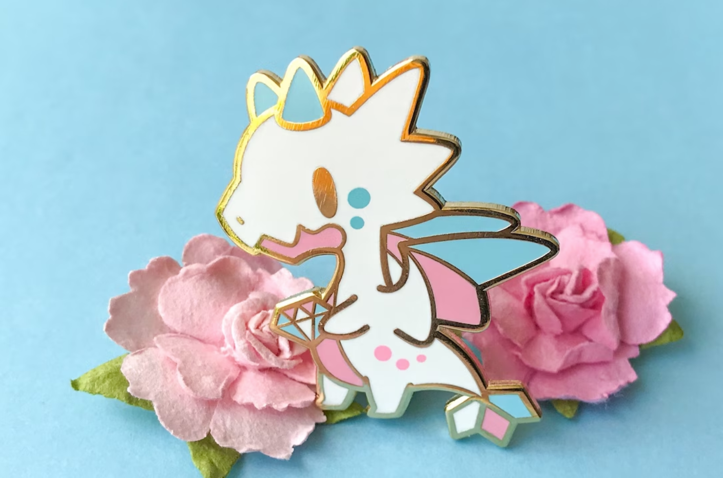 Trans Pride Dragon Enamel Pin with a cute white, pink and blue kawaii dragon holding a gemstone