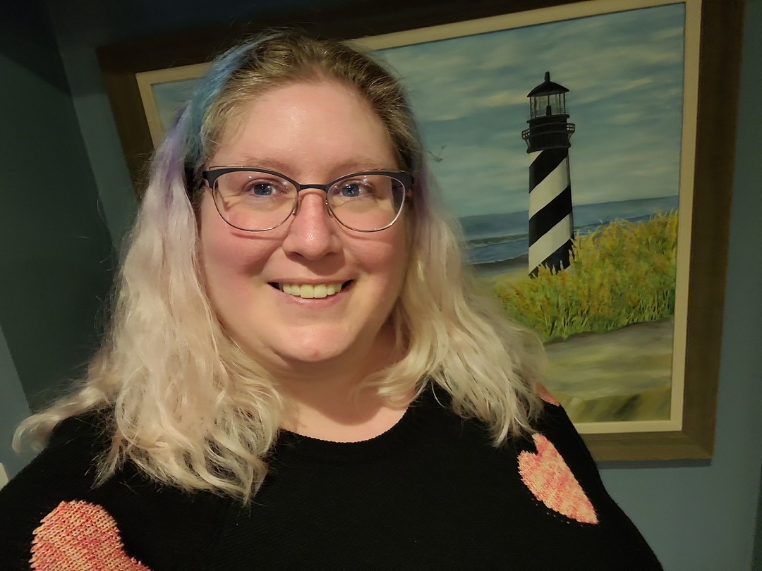 Lindley, a fat white woman, in glasses and standing in front of a painting of a lighthouse