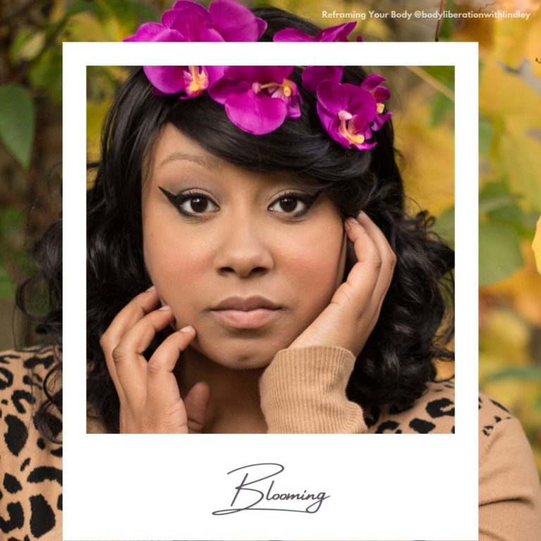 A Black woman gazing at the camera with her hands at the sides of her face, with a bright pink floral crown. A faux polaroid frame is on top with today's word written on the frame.