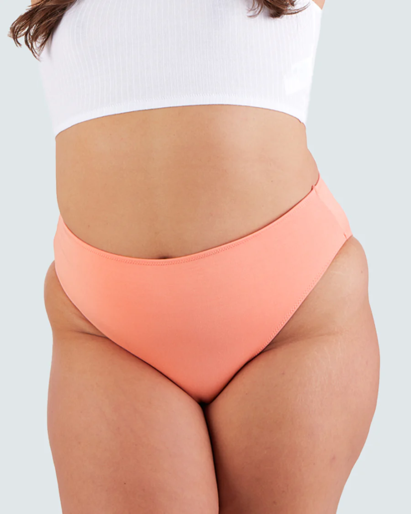 A thin woman wearing a white crop top and a pair of peach panties