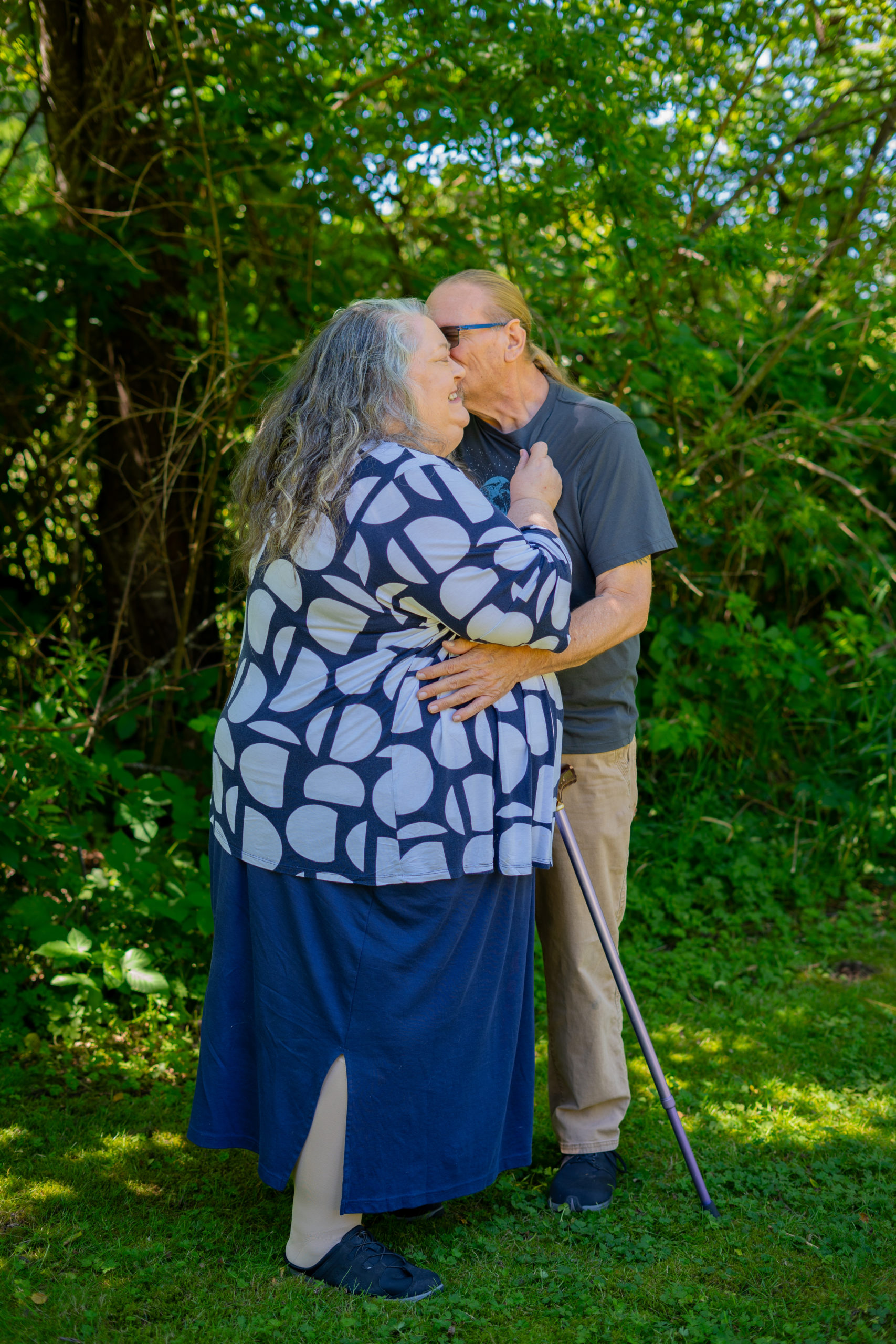 An older, mixed-size and disabled couple exchange a kiss during a body-positive stock photo shoot.