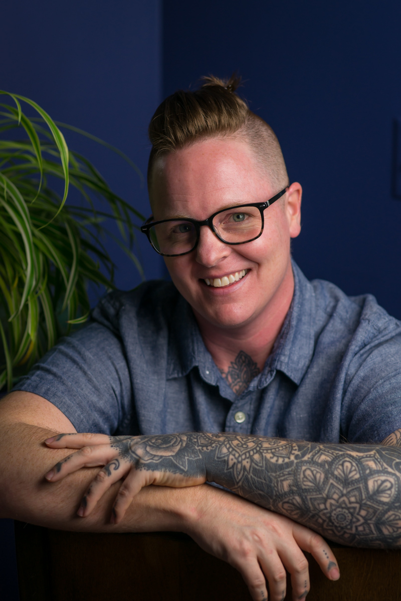 A non-binary small business owner with hair tied back and tattoos at an LGBT friendly business branding photo shoot in Seattle, WA.
