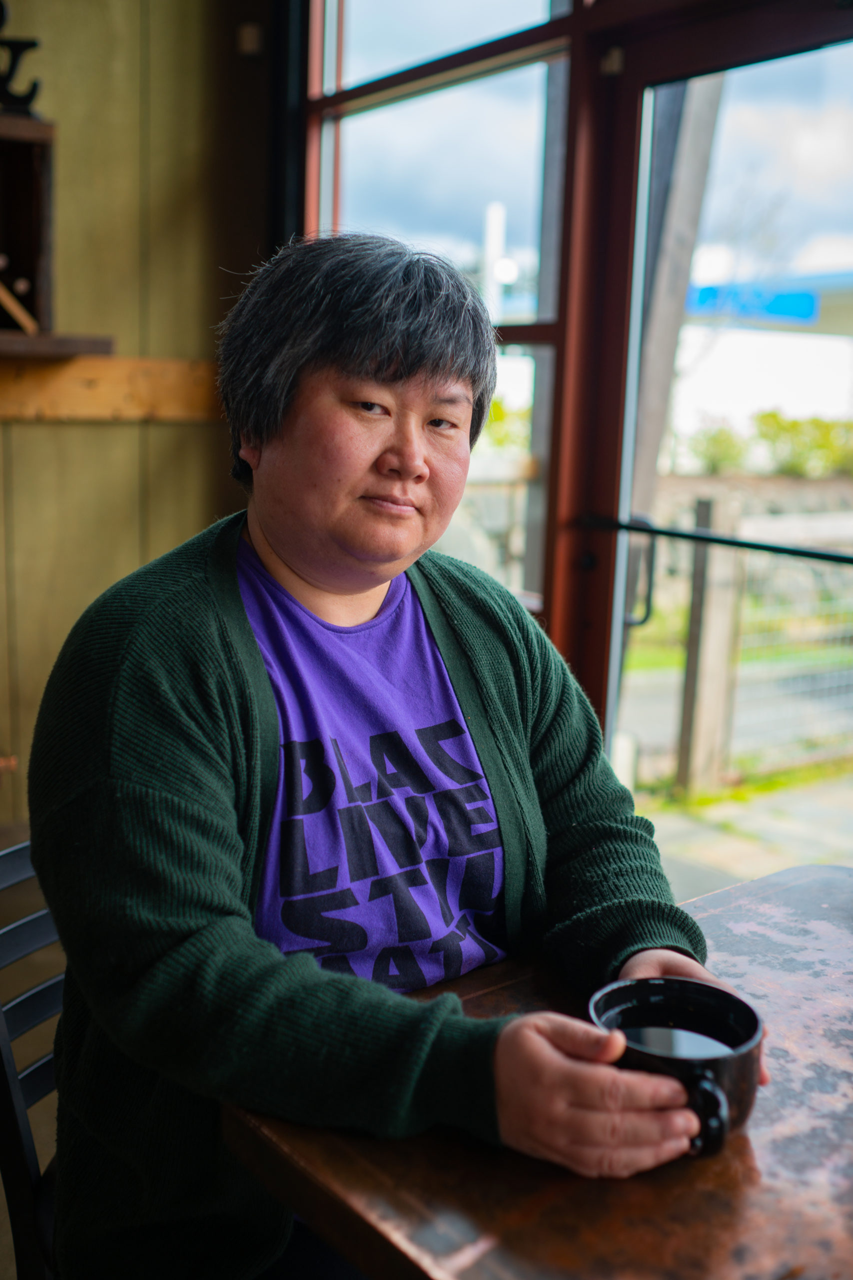 A Chinese-American woman at a Pacific Northwest coffee shop during a photoshoot with a body-positive portrait photographer.