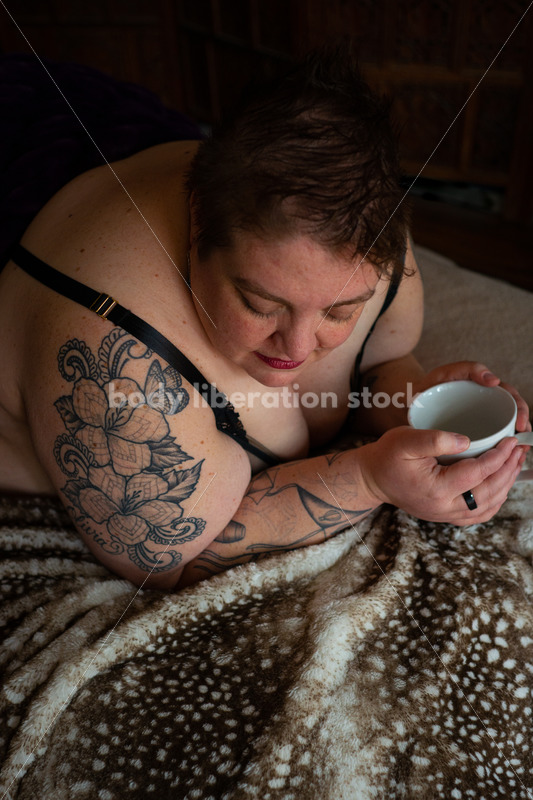Body-Positive Stock Photo: Plus Size Woman Relaxing on Soft Blankets Holding a Cup - Body Liberation Photos