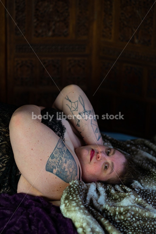 Body-Positive Stock Photo: Plus Size Woman Relaxing on Soft Blankets with a Daring Expression - Body Liberation Photos