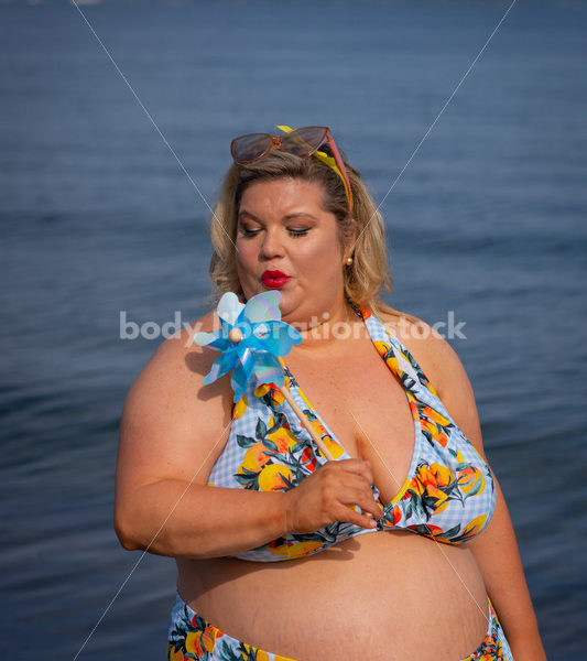 Body-Positive Stock Photo: Plus Size Woman in a Blue Floral Swimsuit Posing with a Matching Pinwheel - It's time you were seen ⟡ Body Liberation Photos