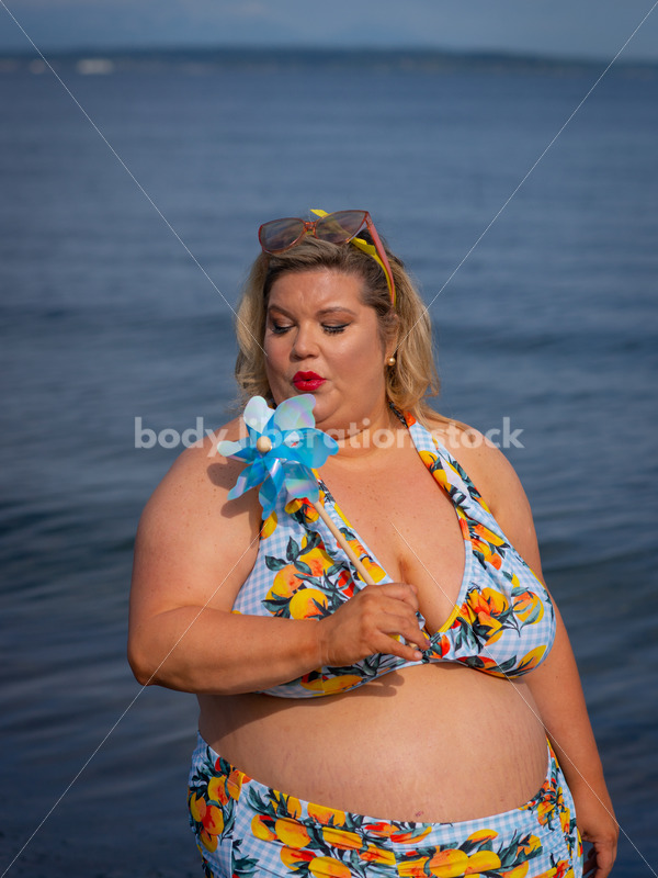 Body-Positive Stock Photo: Plus Size Woman in a Blue Floral Swimsuit Posing with a Matching Pinwheel - It's time you were seen ⟡ Body Liberation Photos