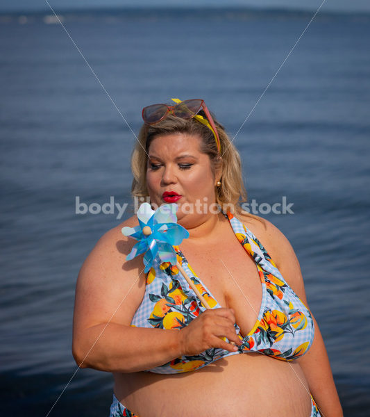 Body-Positive Stock Photo: Plus Size Woman in a Blue Floral Swimsuit Posing with a Matching Pinwheel - It's time you were seen ⟡ Body Liberation Photos