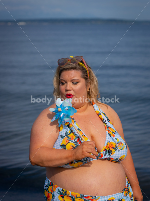 Body-Positive Stock Photo: Plus Size Woman in a Blue Floral Swimsuit Posing with a Matching Pinwheel - It's time you were seen ⟡ Body Liberation Photos