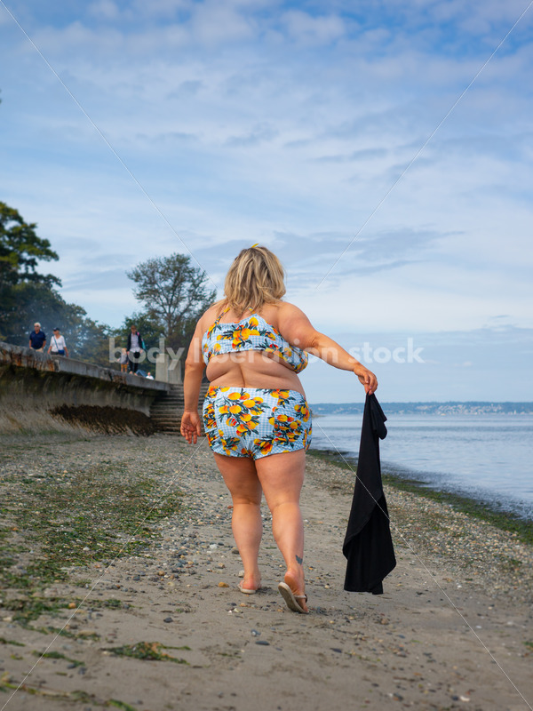 Body-Positive Stock Photo: Plus Size Woman in a Blue Swimsuit Walks Along the Beach Holding a Coverup - It's time you were seen ⟡ Body Liberation Photos