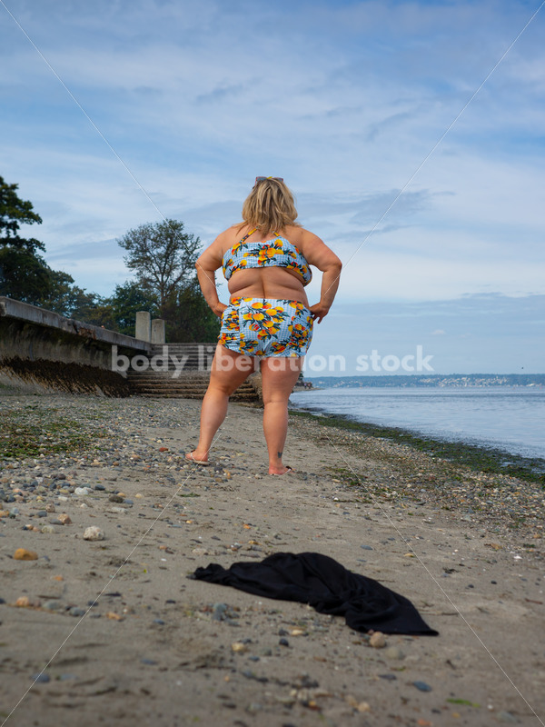 Body-Positive Stock Photo: Plus Size Woman in a Blue Swimsuit Walks Along the Beach Leaving a Coverup Behind on the Sand - It's time you were seen ⟡ Body Liberation Photos