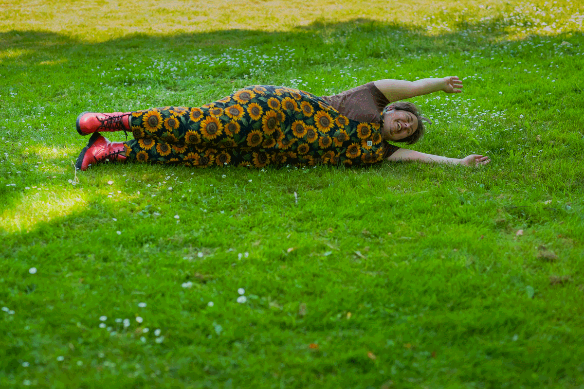 An animation of a laughing fat non-binary person rolling down a grassy hill during a queer-friendly, body-positive Seattle business portrait session.