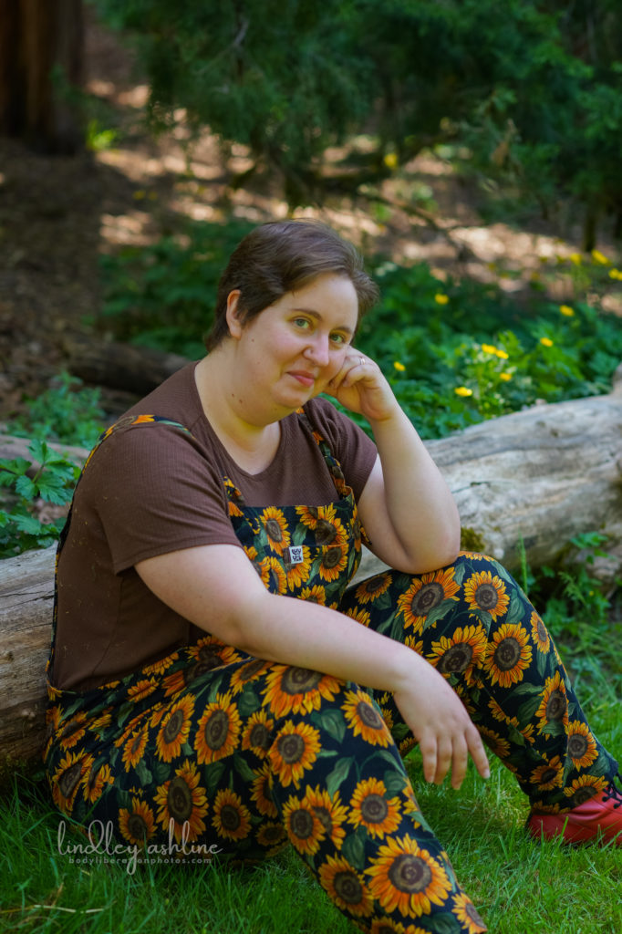 A Seattle neurodivergent life coach sits against a log in a park at a Seattle small business branding photo session for life coaches.