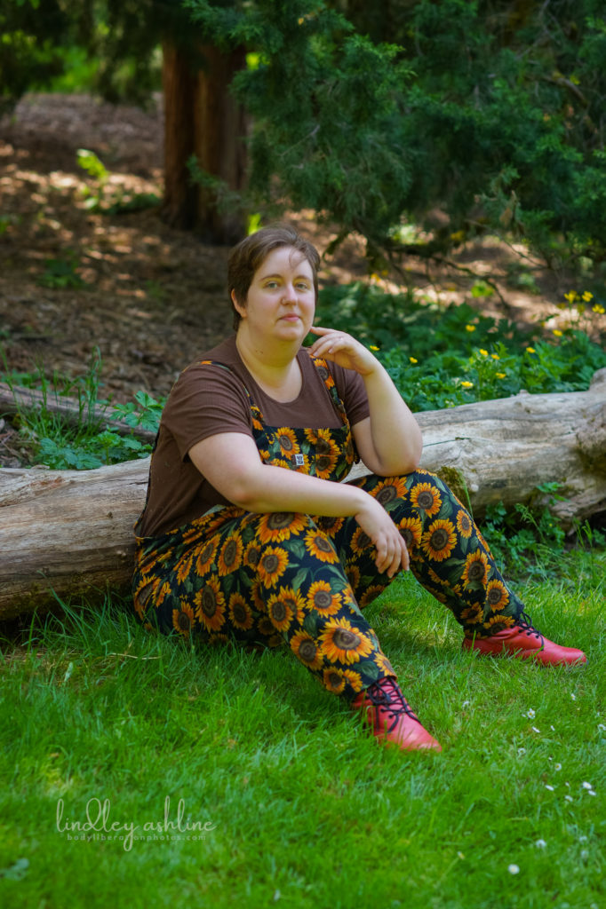 A Seattle neurodivergent life coach sits against a log in a park at a Seattle small business branding photo session for life coaches.