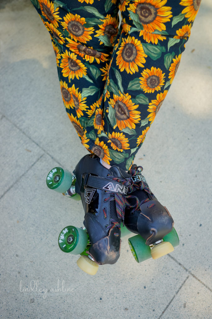 A close-up of a smaller fat person's roller skates and legs outdoors.