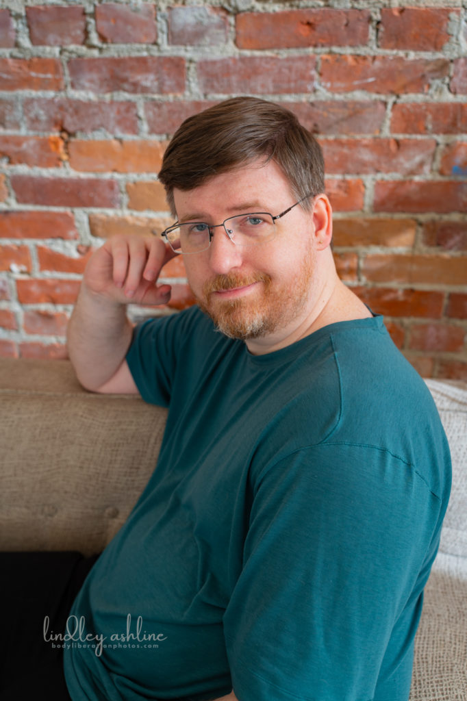 An midsize white man in a t-shirt looks at the camera with a wry expression at a Pacific Northwest autism-friendly business branding photo shoot.