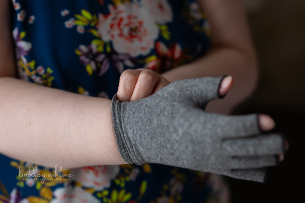 A chronically ill plus-size white woman pulls on a compression glove at a Seattle body-positive business branding session.